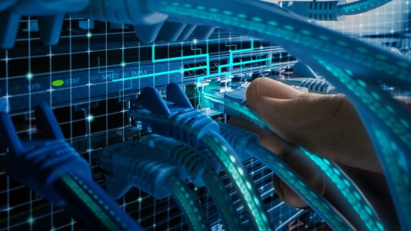 a hand plugging an ethernet cable into a device