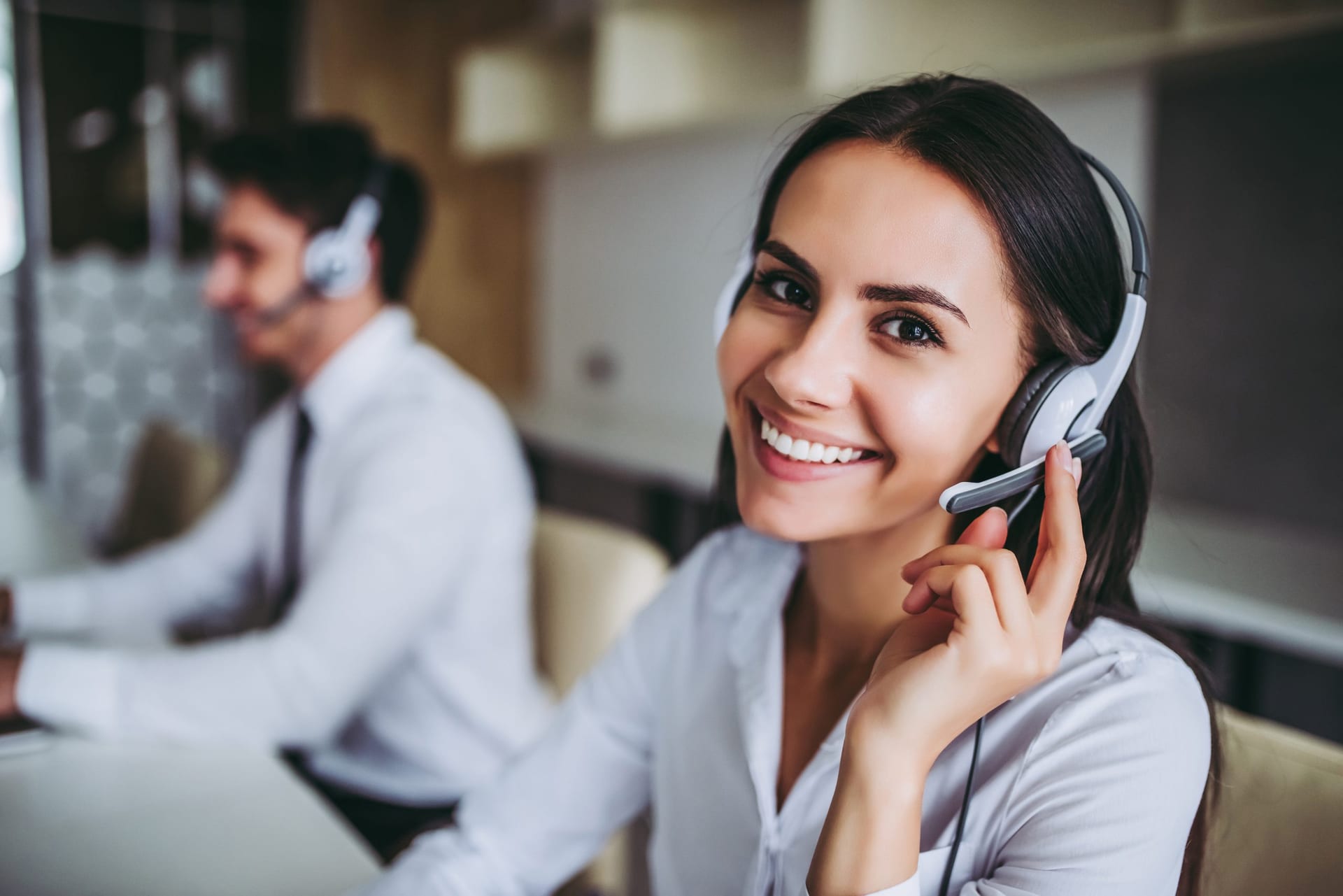 lady touching her phone headset and smiling at the camera while providing customer service