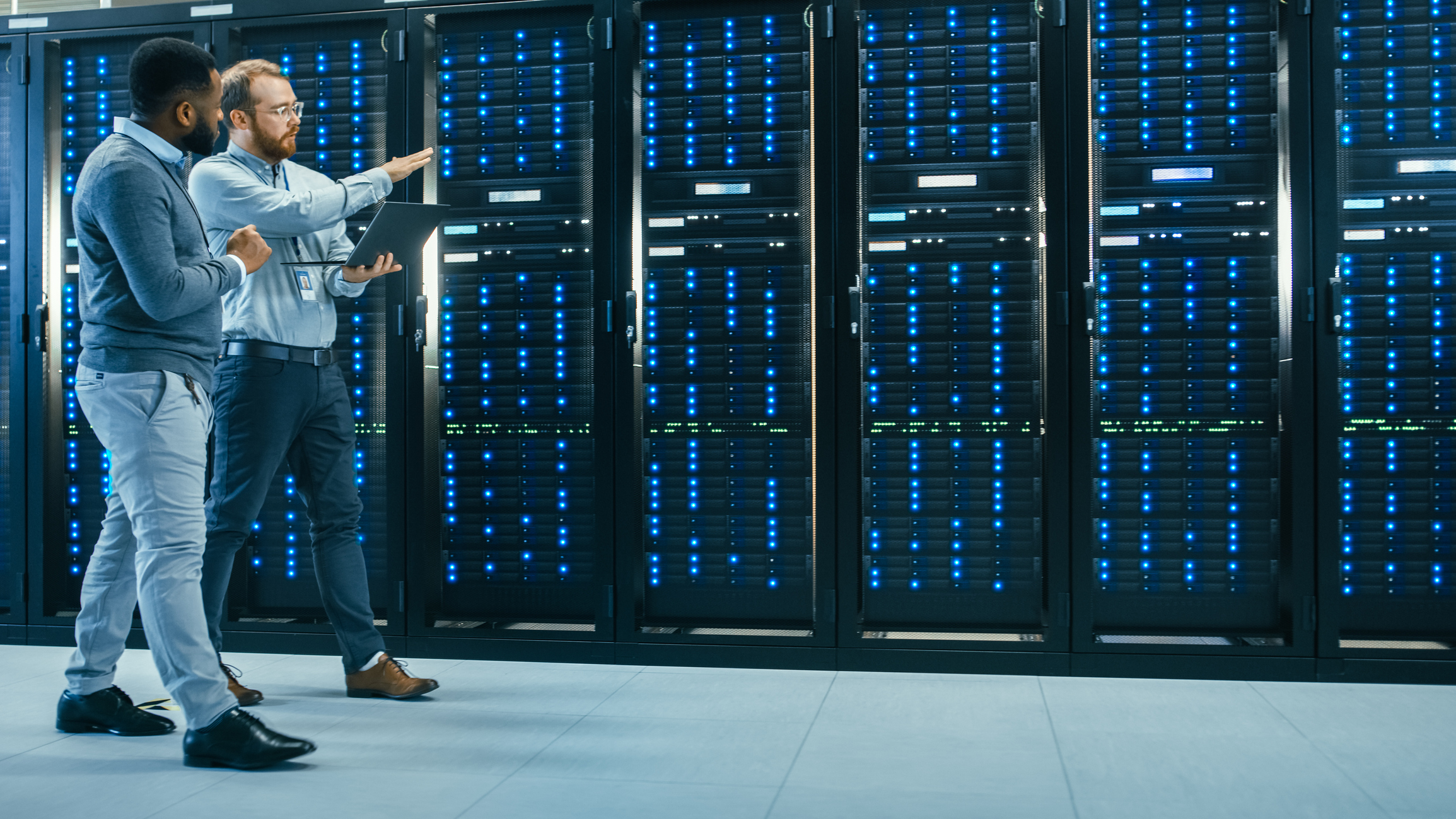 a rack of computer servers and network equipment on show being monitored by two people