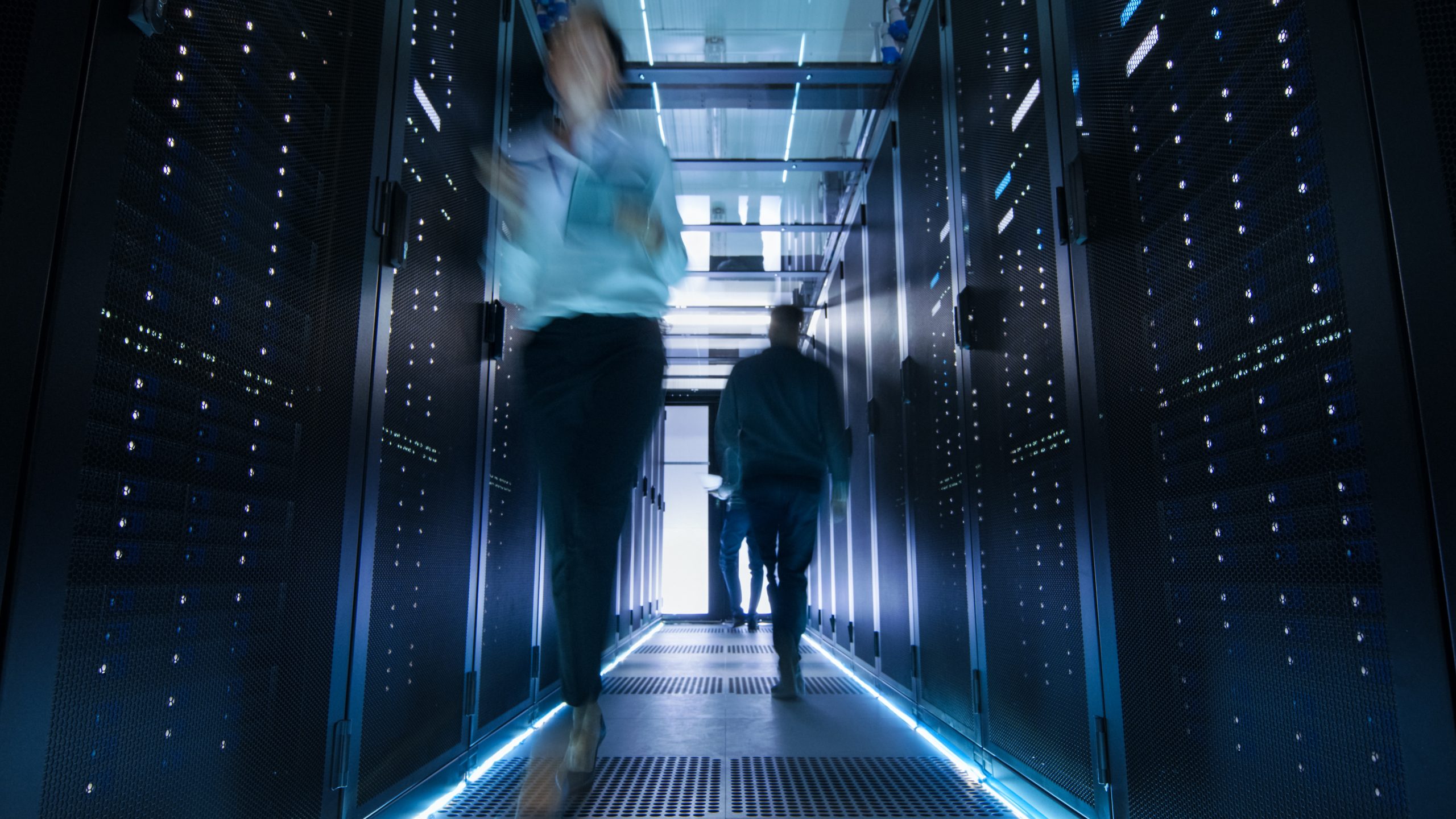 the inside of a data centre with people walking quickly through it showing urgency