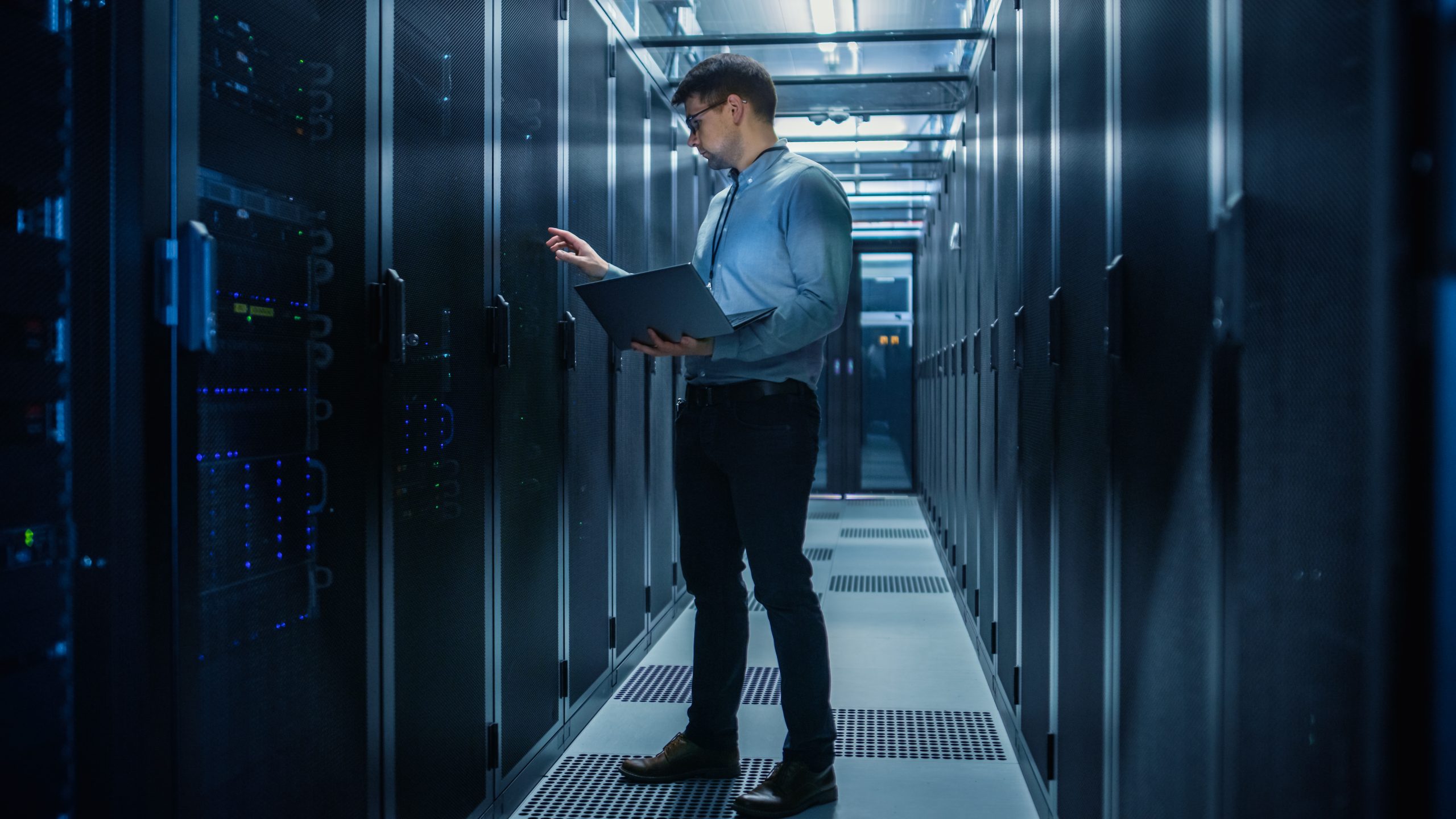 a network engineer hard at work in a data centre looking at a computer