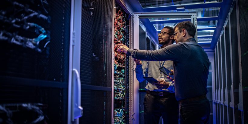 two male IT professionals looking at a server rack troubelshooting