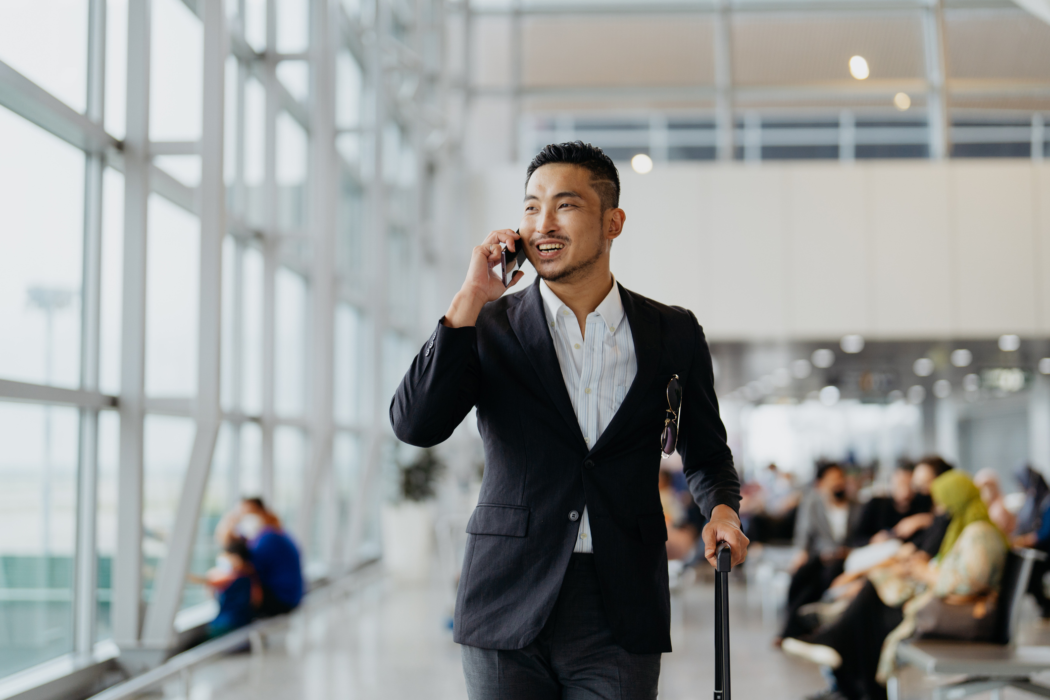 Confident Asian businessman talking on the phone in airport terminal